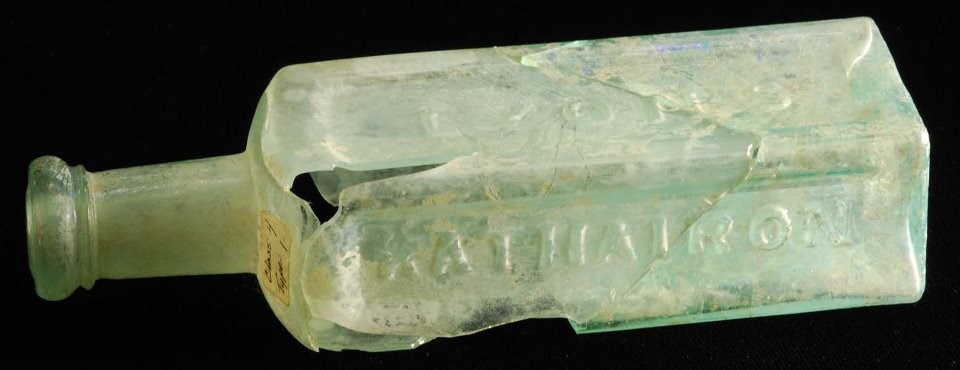 Lyon's Bottle Greenish glass bottle, broken and pieced together, with raised lettering.