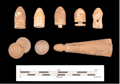 Five different cylindrical bullets, one with a pinched midsection and another with hole in the middle. Three round buttons on bottom left. Long, cone-shaped, brass tip of a scabbard, on bottom right.