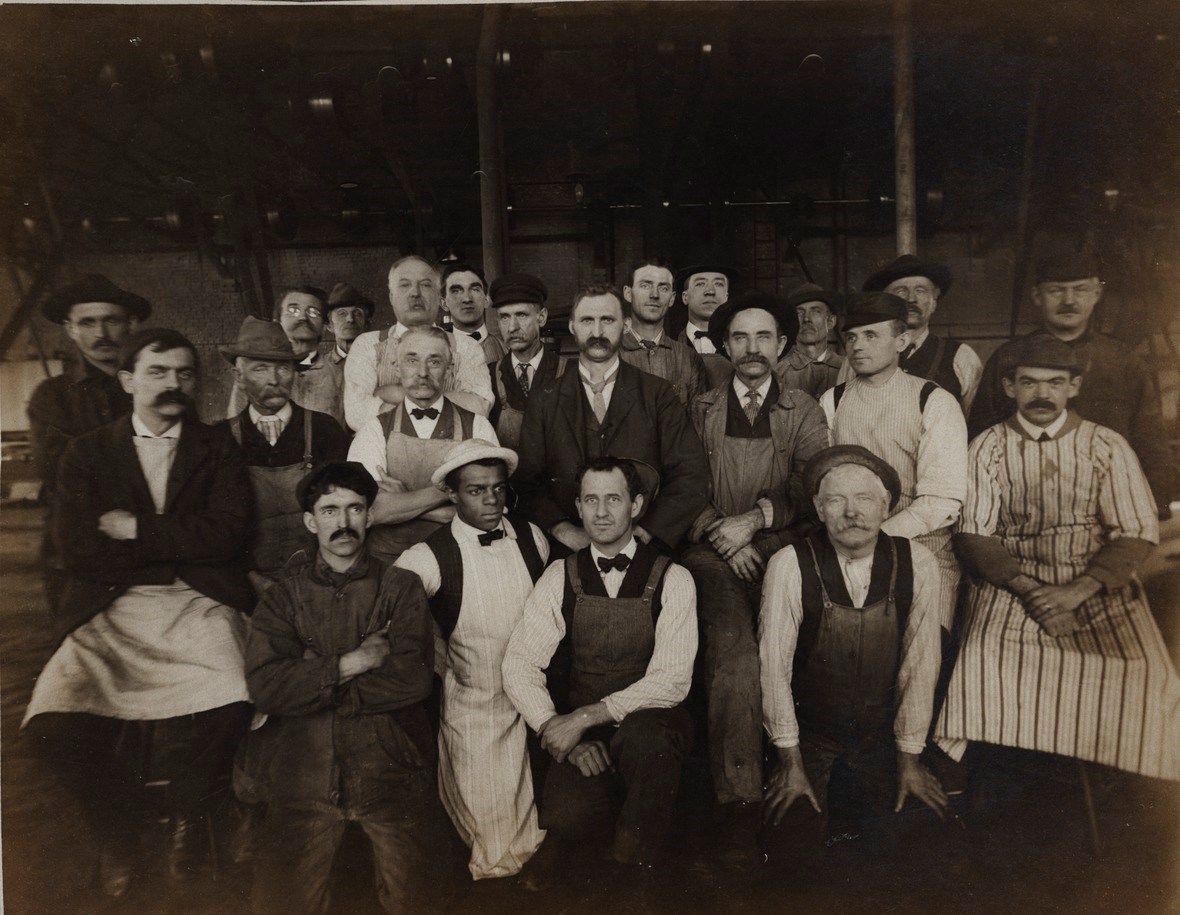 Group photo of workers wearing aprons and coveralls.