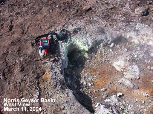 Close view of vent in ground and piece of red equipment next to vent.
