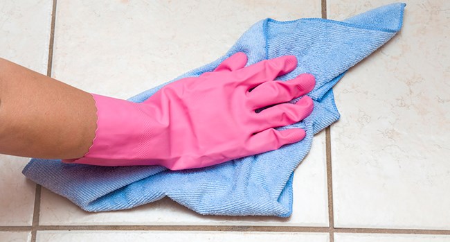 Photo of a gloved hand cleaning with a cloth.