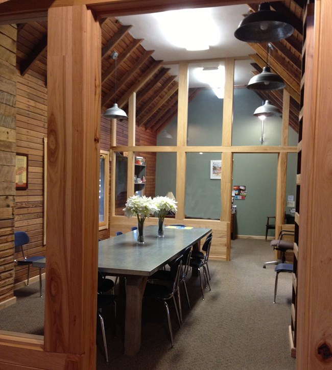 Second floor of Amana Visitor Center Small room with wood plank walls and a table with flower vases.