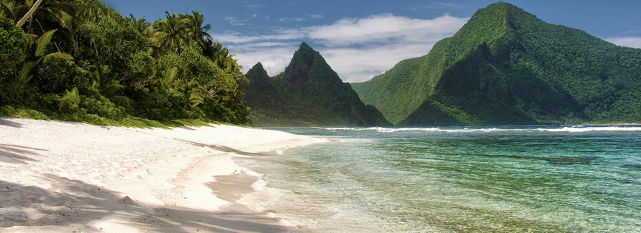 Ofu Island Sandy beach and turquoise waters with forested tropical mountain in distance