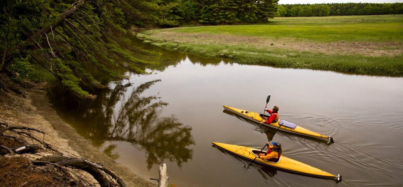 Kayakers paddle past extensive salt marshes along the York River in Maine Kayakers paddle past extensive salt marshes along the York River in Maine