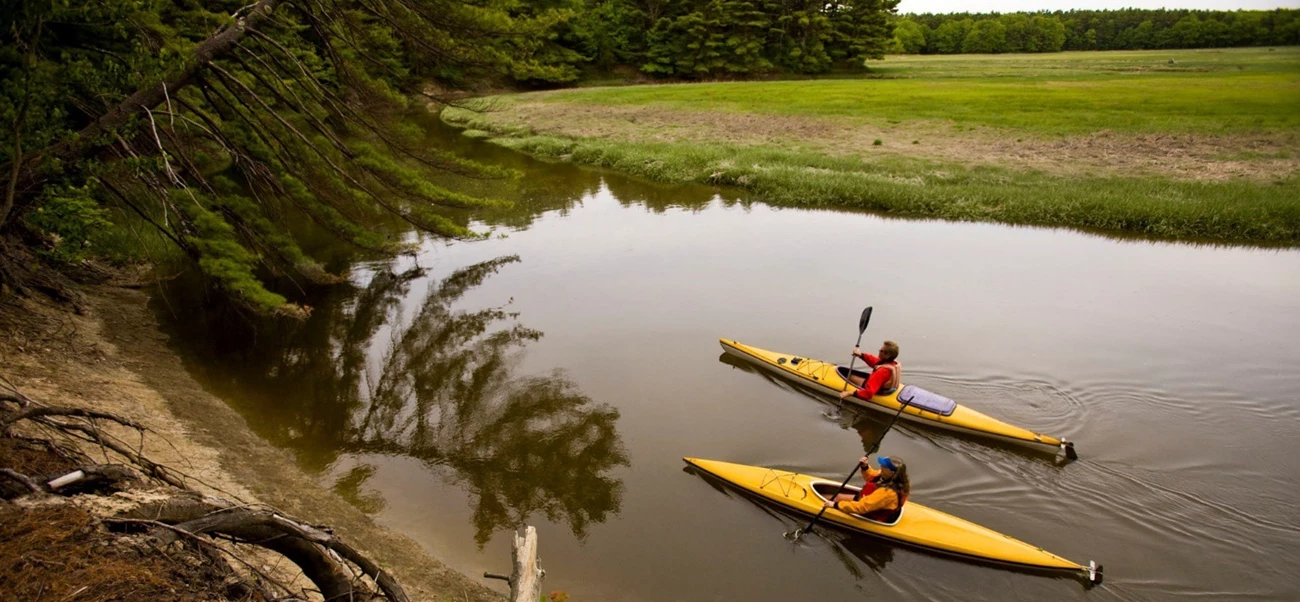 Kayakers paddle past extensive salt marshes along the York River in Maine Kayakers paddle past extensive salt marshes along the York River in Maine