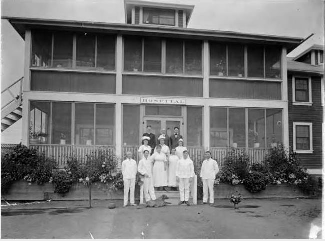 a half dozen nurses standing in front of a two story building