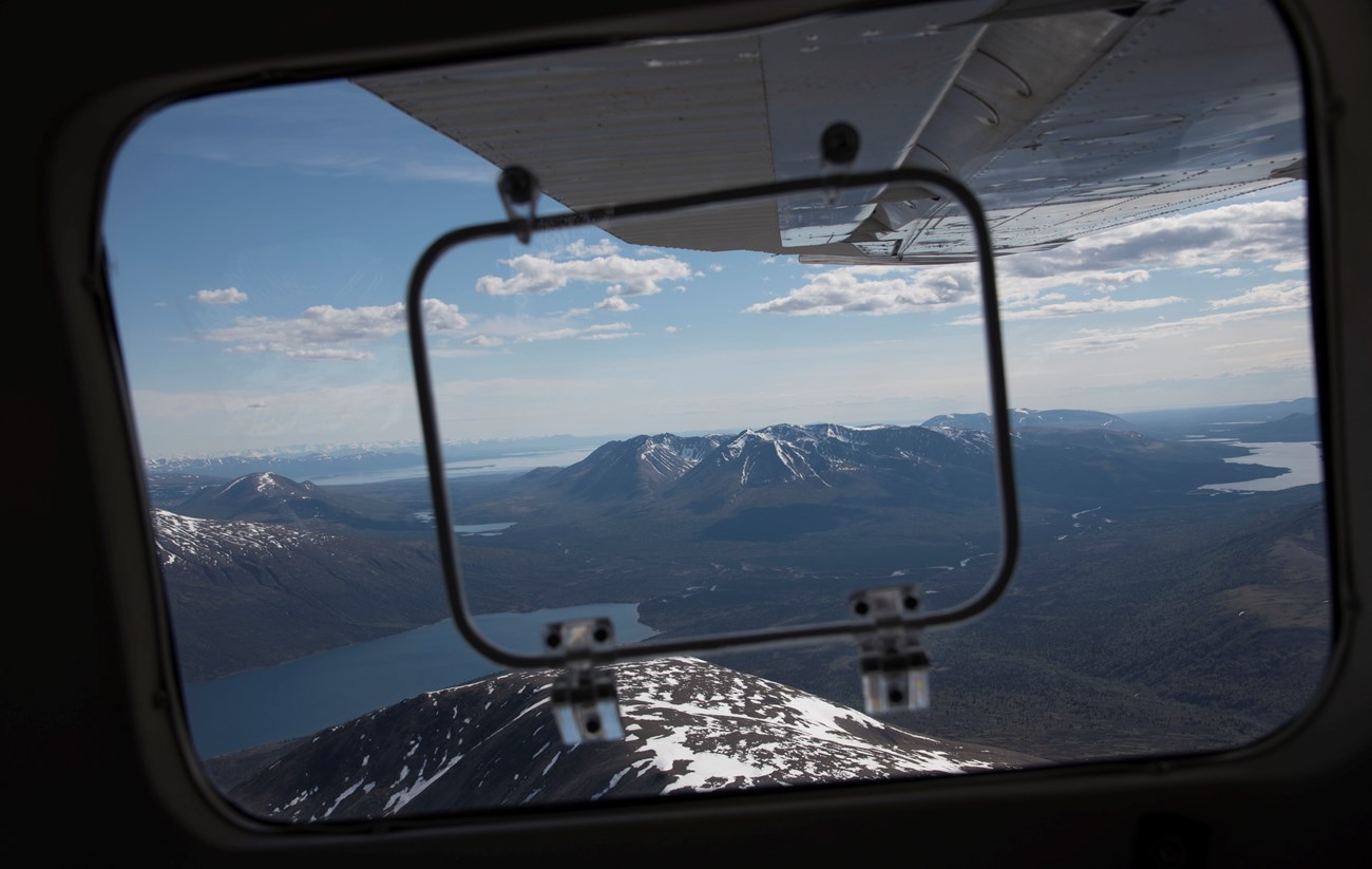 A view of mountains and lakes from a plane window