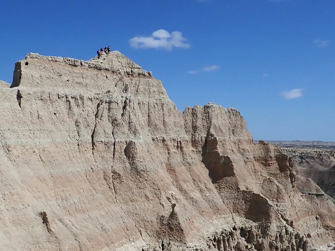 Hikers walk along the ridge of a cliff