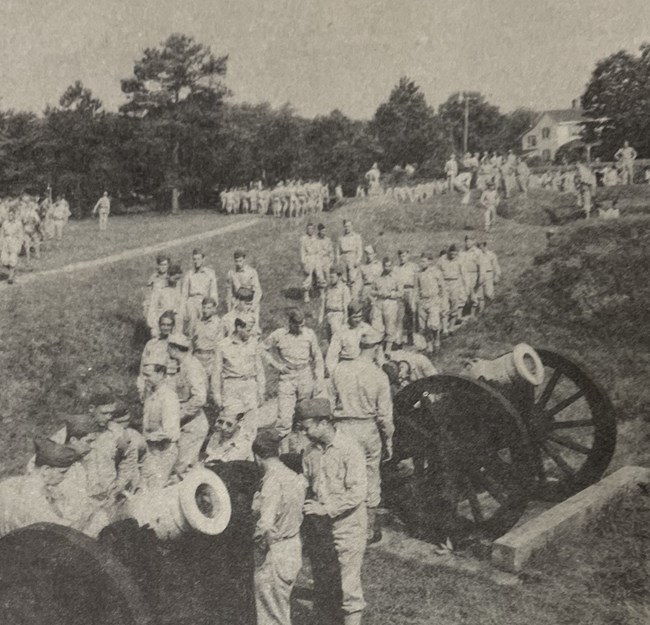 Lots of US Army soldiers around cannon mounted on carriages in a field