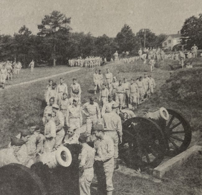 WWII soldiers examining cannon Lots of US Army soldiers around cannon mounted on carriages in a field