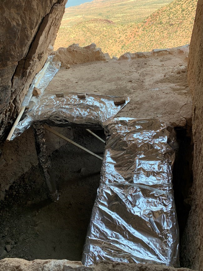 Cliff dwelling roof wrapped in preparation for wildfire