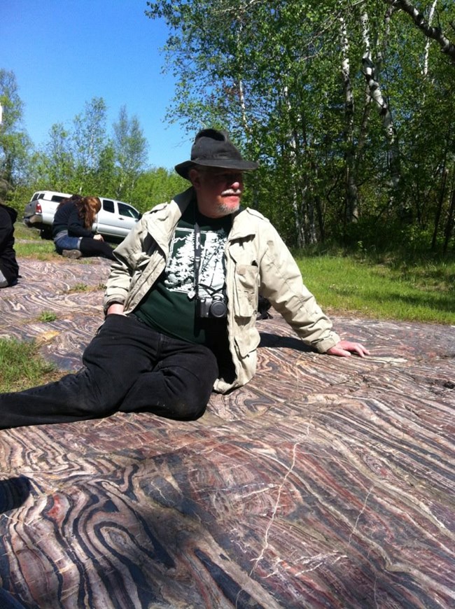 Dr. Plotnick sitting on the Precambrian banded iron formations in Minnesota.