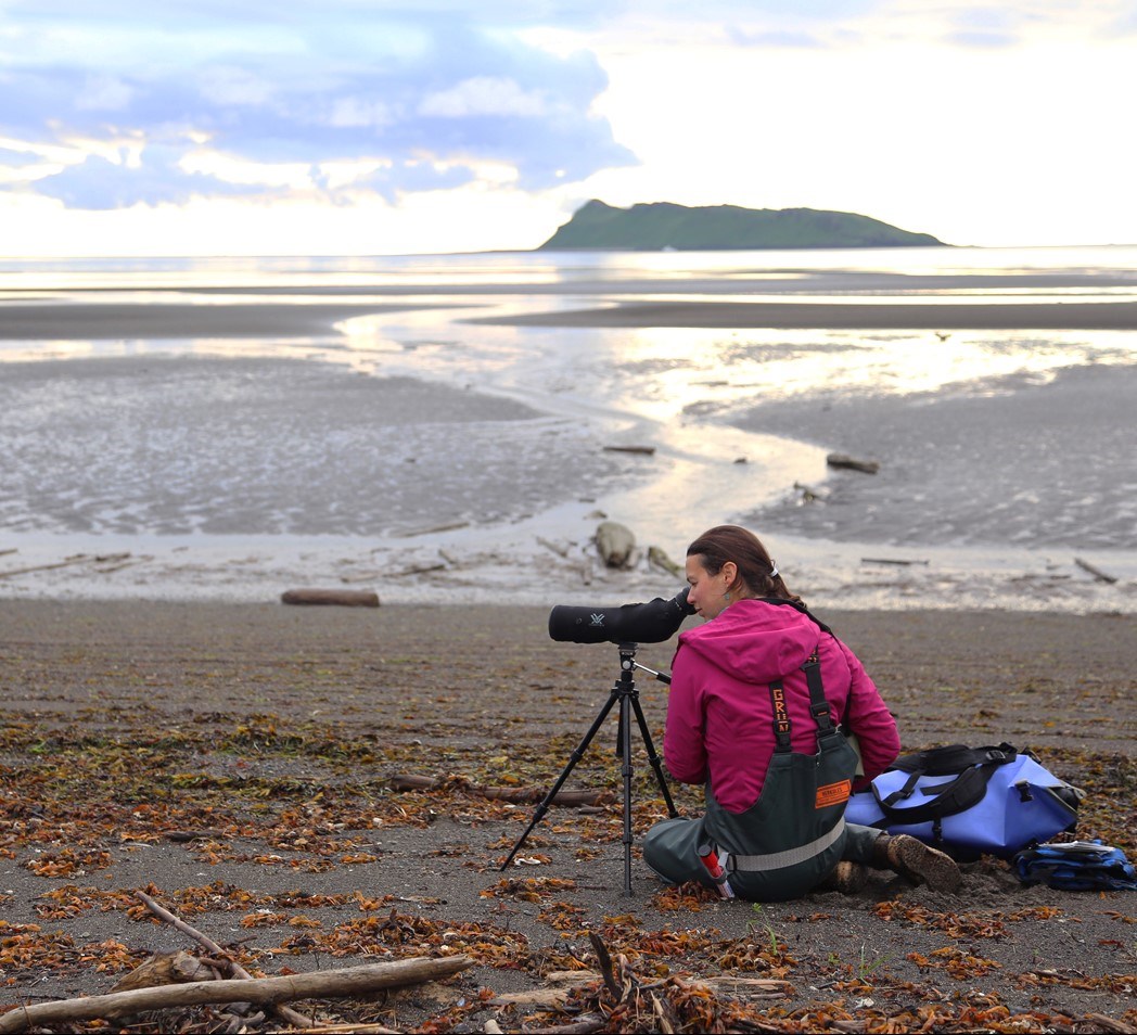 Scientist making observations with telescope on beach.