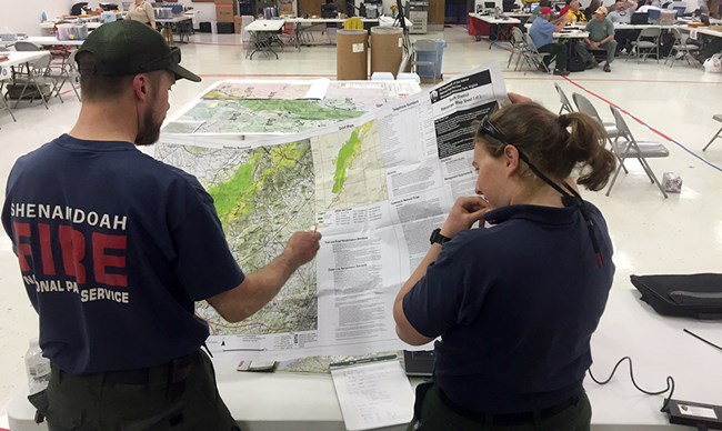 Two people look at a plotter-size document.