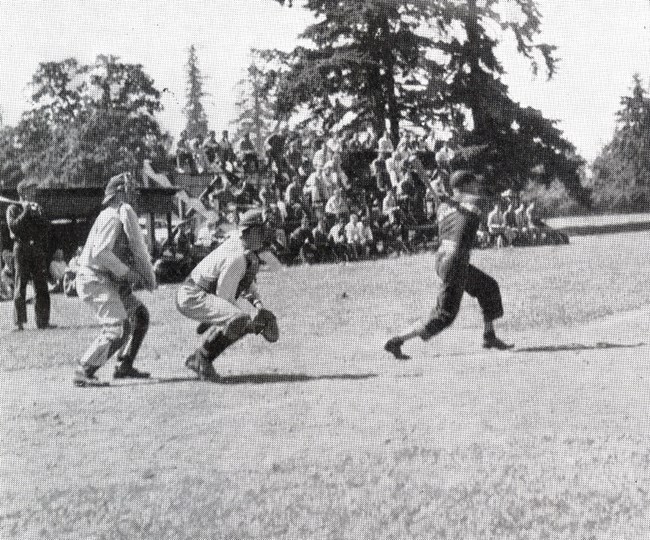 CCC baseball game Black and white photo of baseball game with audience on bleachers in background.