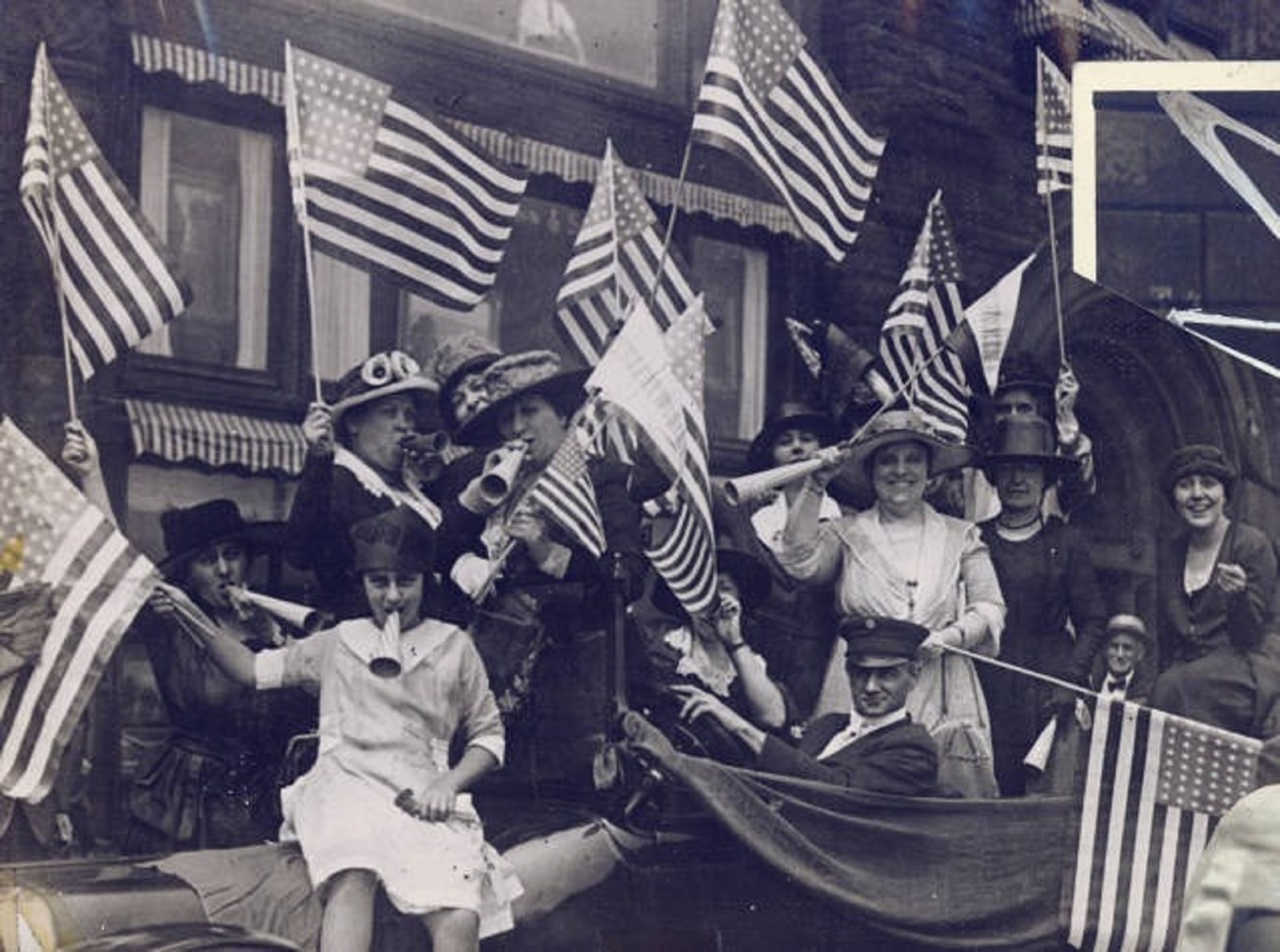 Women celebrating by waving flags and blowing horns. Carrie Chapman Catt albums, Special Collections Department, Bryn Mawr College Library