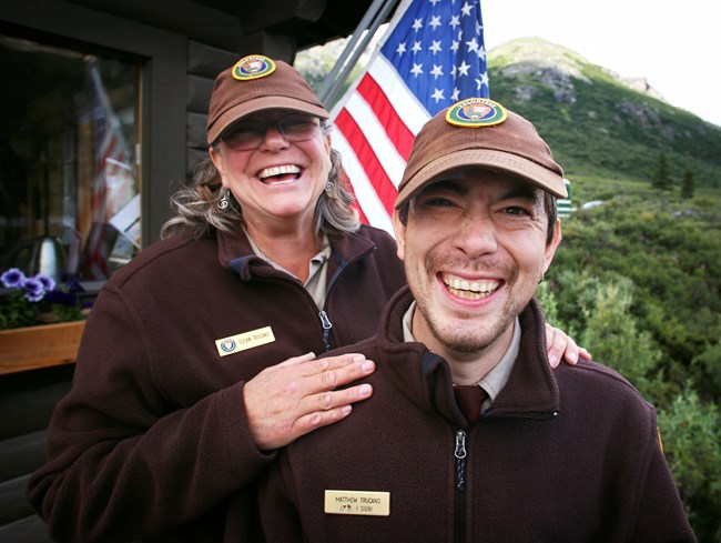 Smiling young man with older woman standing behind him.