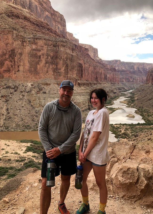A father and daughter pose at an overlook of the colorado river.