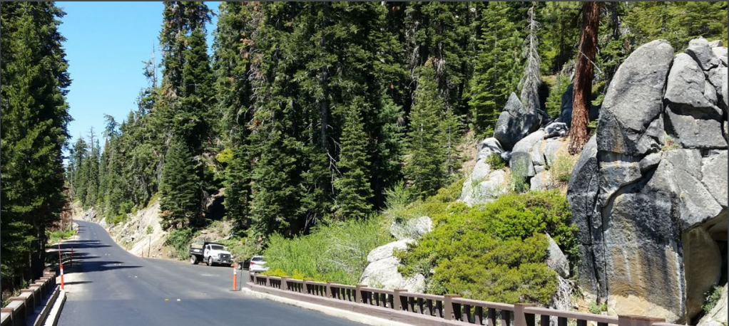 a large rock on right and newly paved road