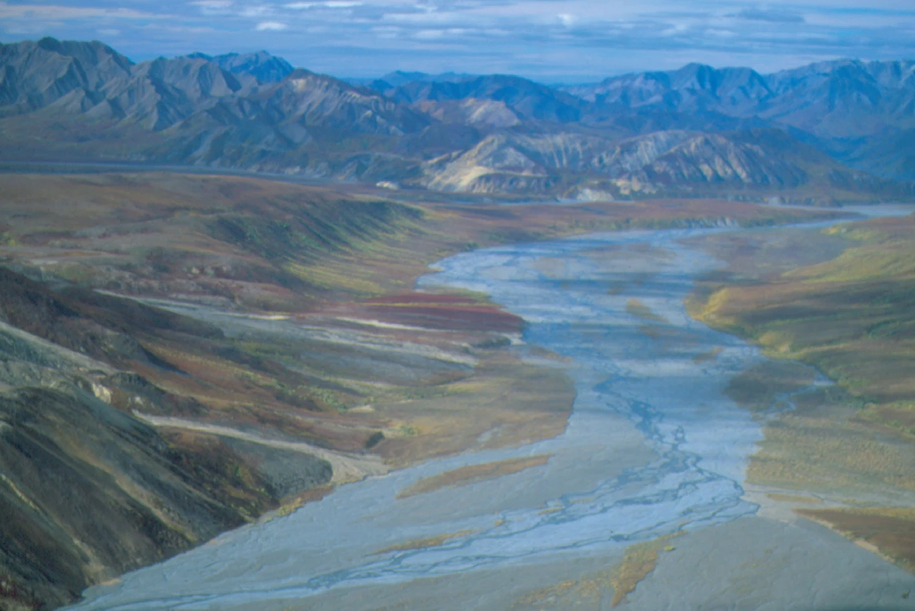 toklat river by mike green wide river with mountains in the distance
