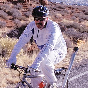 a bicyclist with the Olympic torch on the back of the bicycle