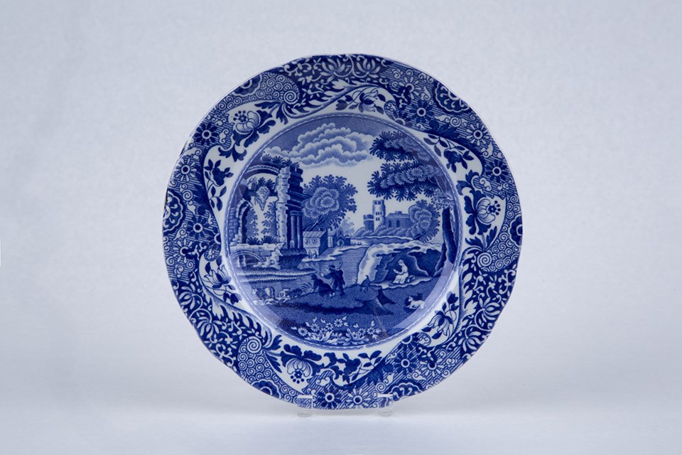 A small plate with a rural scene on it in bright blues.