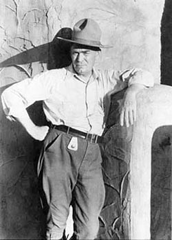 tuma1fig2 Man leans on adobe wall.