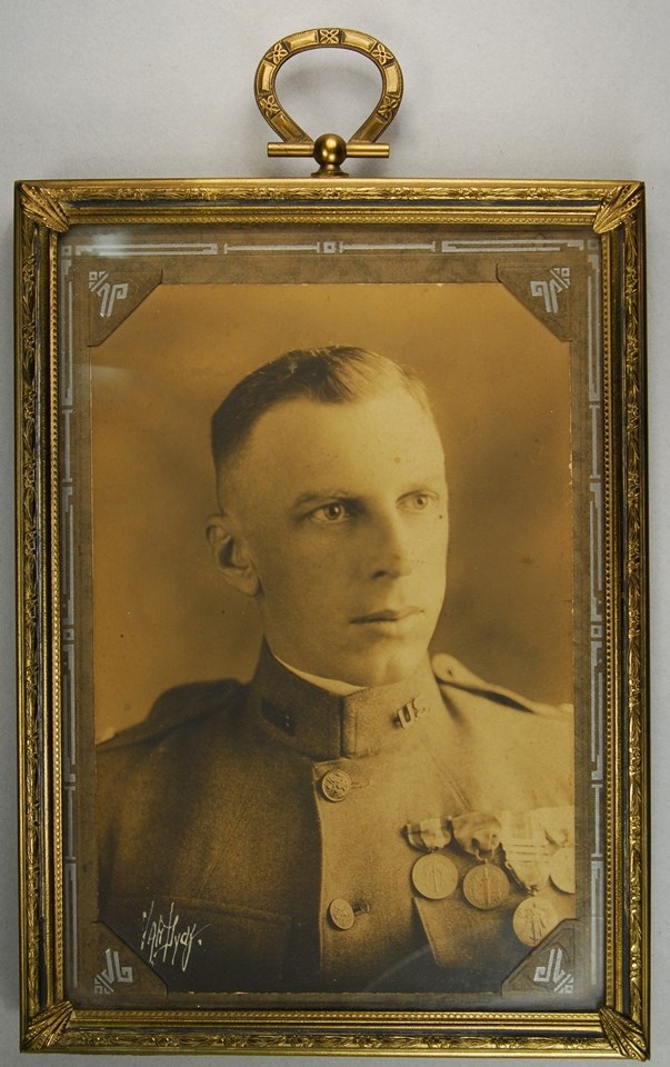 Framed photograph of a man in uniform with four medals attached to his uniform tunic.