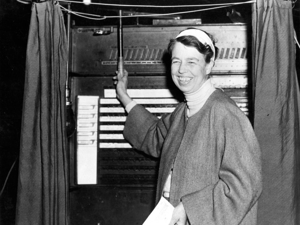 A woman standing in a voting booth.