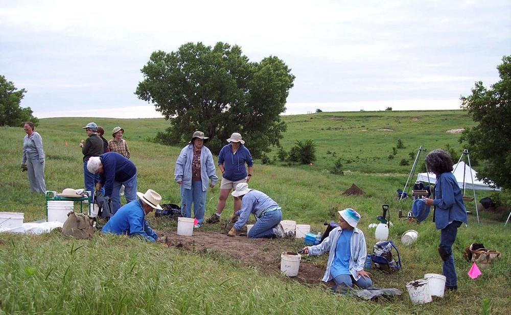 People excavate dirt on a broad landscape background The excavation team at the homesite.