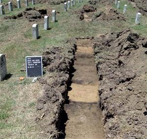 Shallow trenches dug between rows of graves.