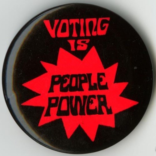 Red and black button with"Voting is People Power," written on it. National Museum of American History, Smithsonian Institution.