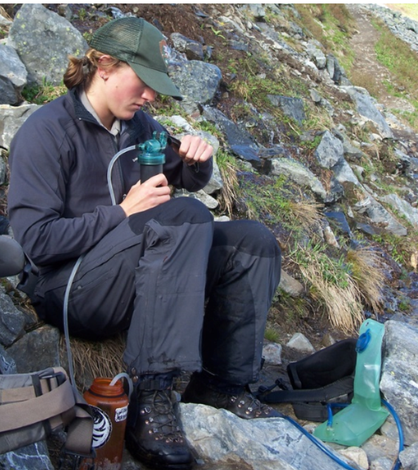 A women uses a water bottle filtration system to clean the water