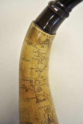 A powderhorn with intricate etchings on it, including rivers and the fort.