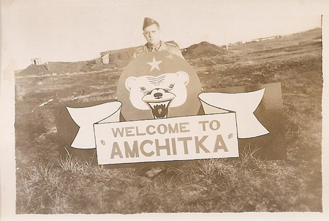 man in uniform standing behind welcome sign