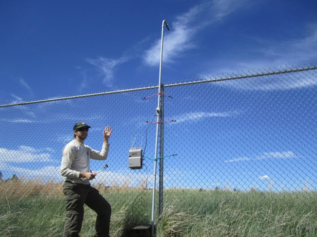 Man in front of a fence with monitoring equipment attached to it