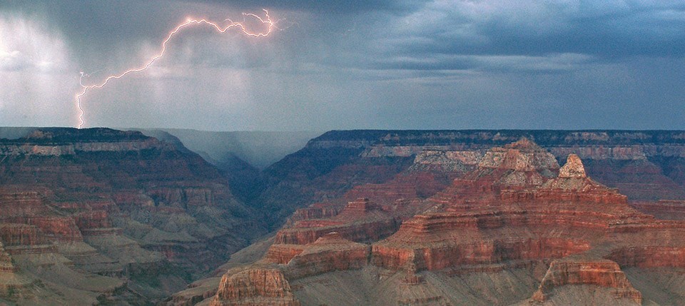Lightning pierces the cloudy rainy sky above the Grand Canyon.
