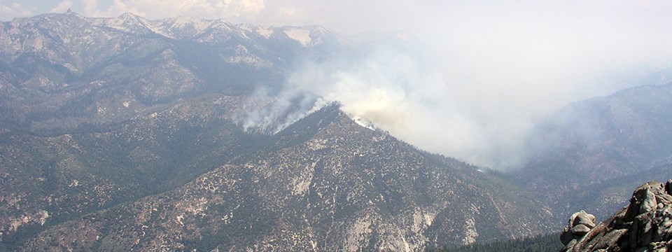 Smoke rises from rocky mountaintop.