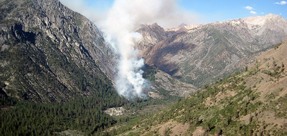 Smoke rises up a narrow canyon.