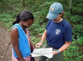 A young woman looks at a map being held by another woman.