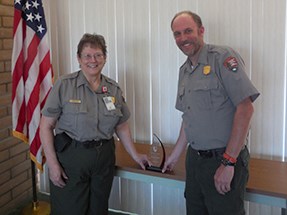 lt= Susan Keys and John Thornburg stand near the award.