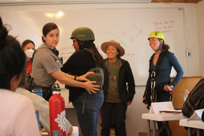 Female participants wear different helmets and gear to illustrate the variety of career options in land management