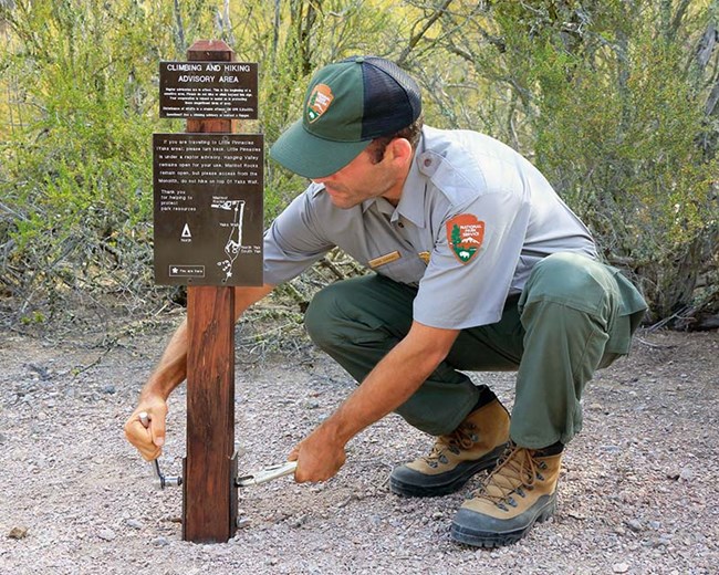 NPS staff installing raptor advisory sign