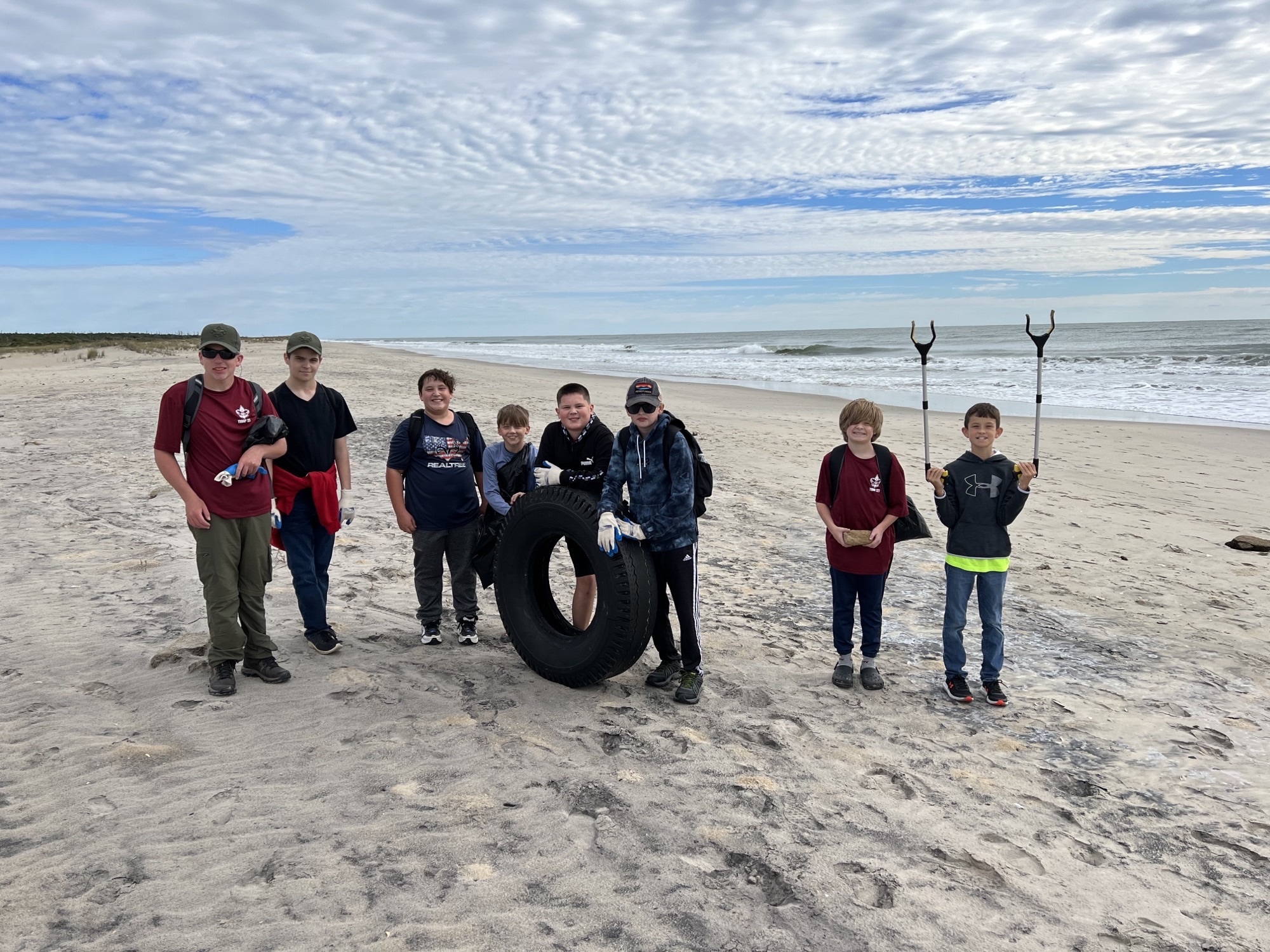 Scout troop on beach removing a large tire during the 2022 Beach Clean Up Scout troop on beach removing a large tire during the 2022 Beach Clean Up