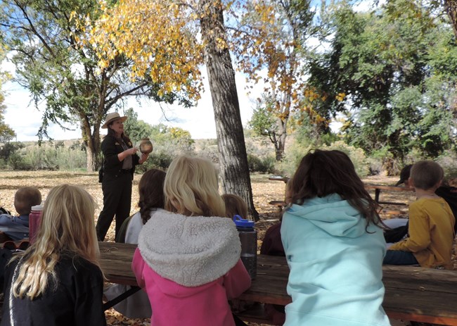 A ranger holding up a replica pot to students.