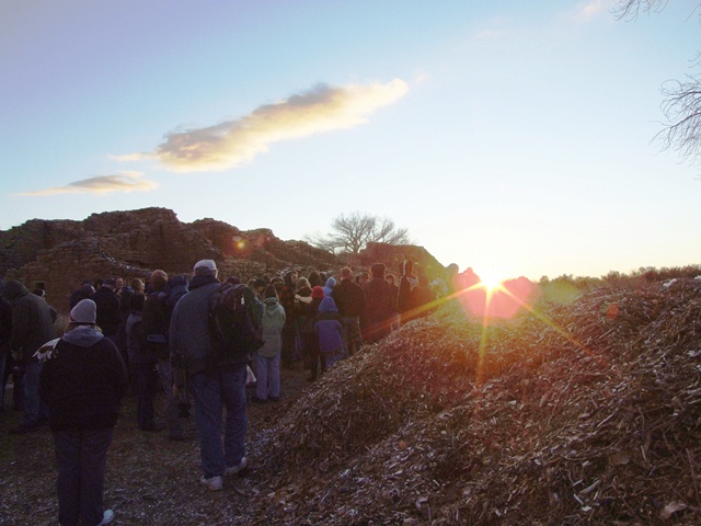 Visitors watch the sunset along a stone wall. Visitors watch the sunset along a stone wall.