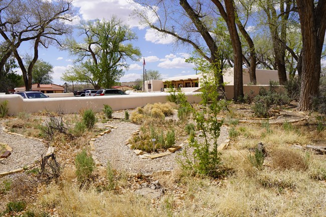 A winding gravel path with labeled native plants along the outside of the path. The visitor center is shown in the background.