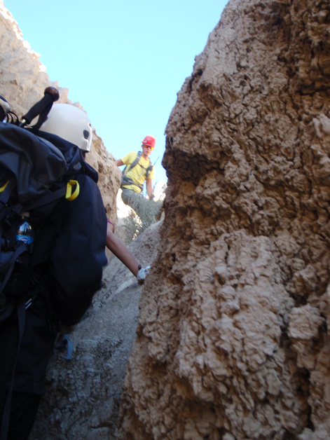 Search and Rescue team members climb through rugged badlands terrain.