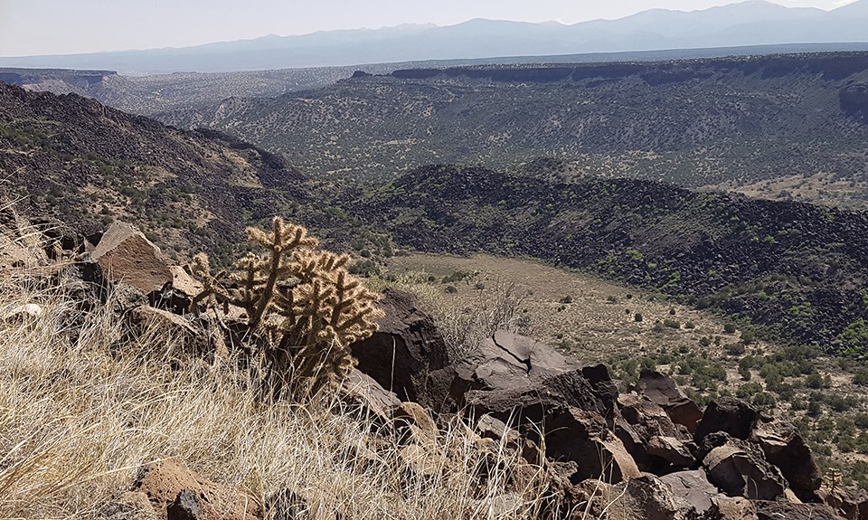 a wide view of a river flowing through a landscape of dark rocks.