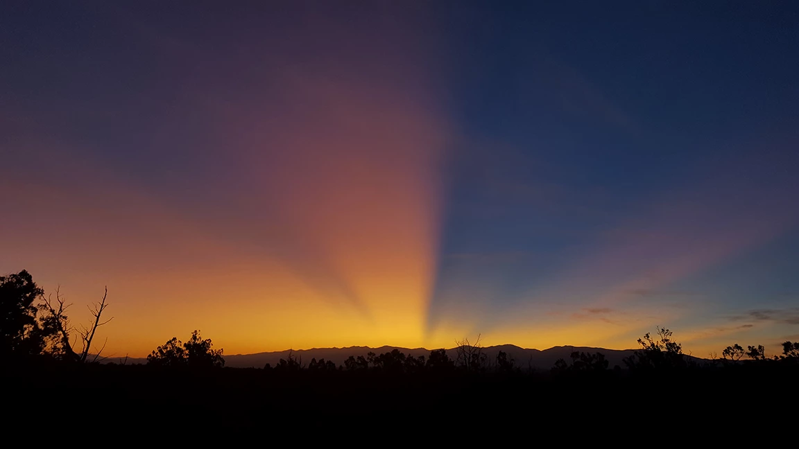 The sun rises over the mountains. The sun rises over a mountainside.